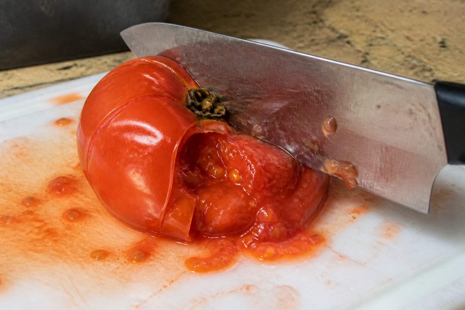 A dull knife crushing a tomato