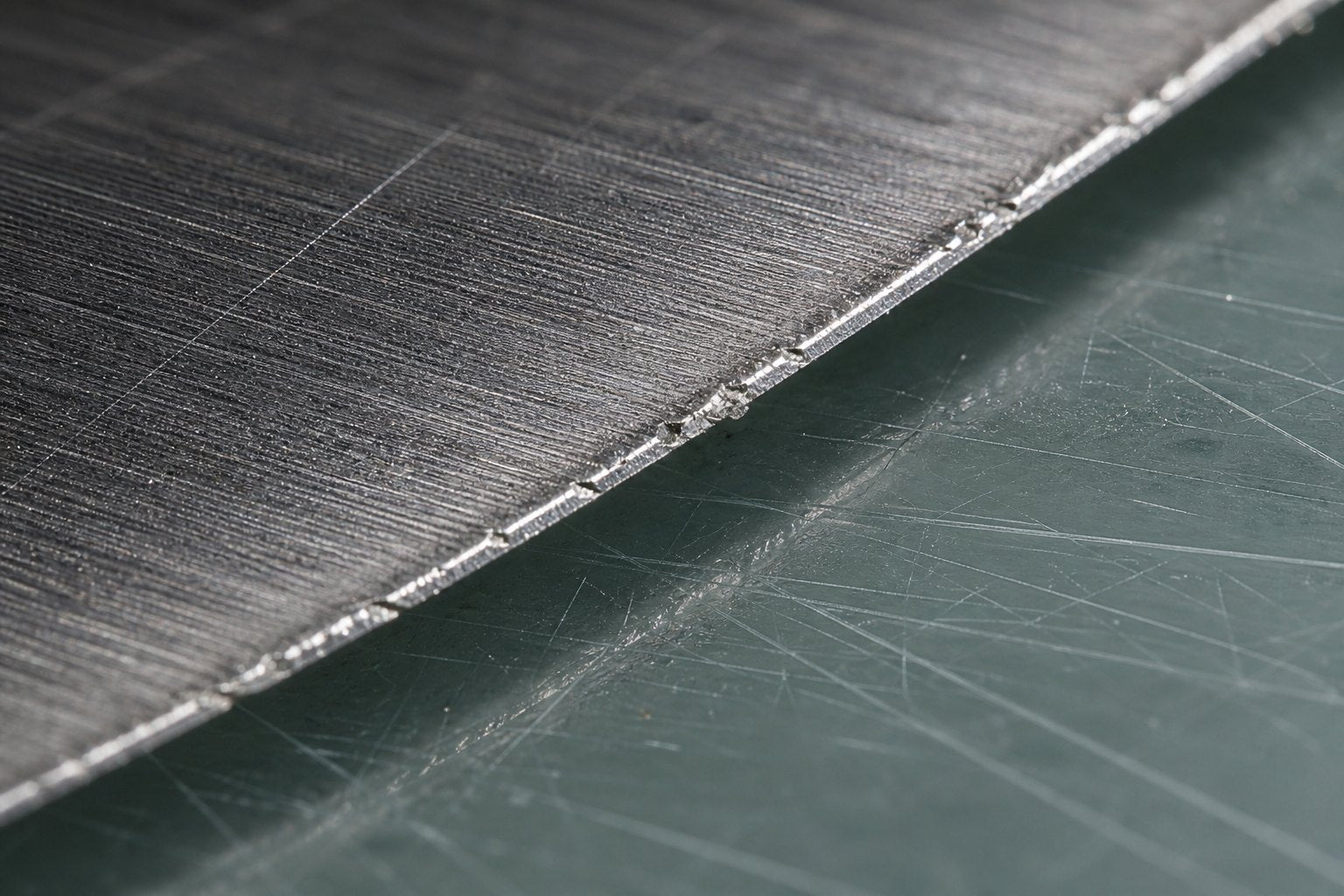 A knife edge chipped and rolled on a glass cutting board