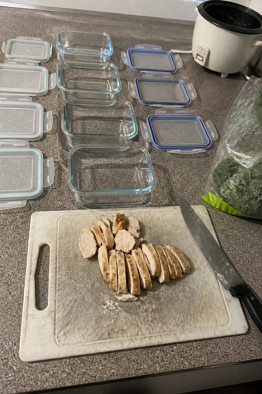 A scarred plastic cutting board with plastic shavings next to empty meal-prep containers