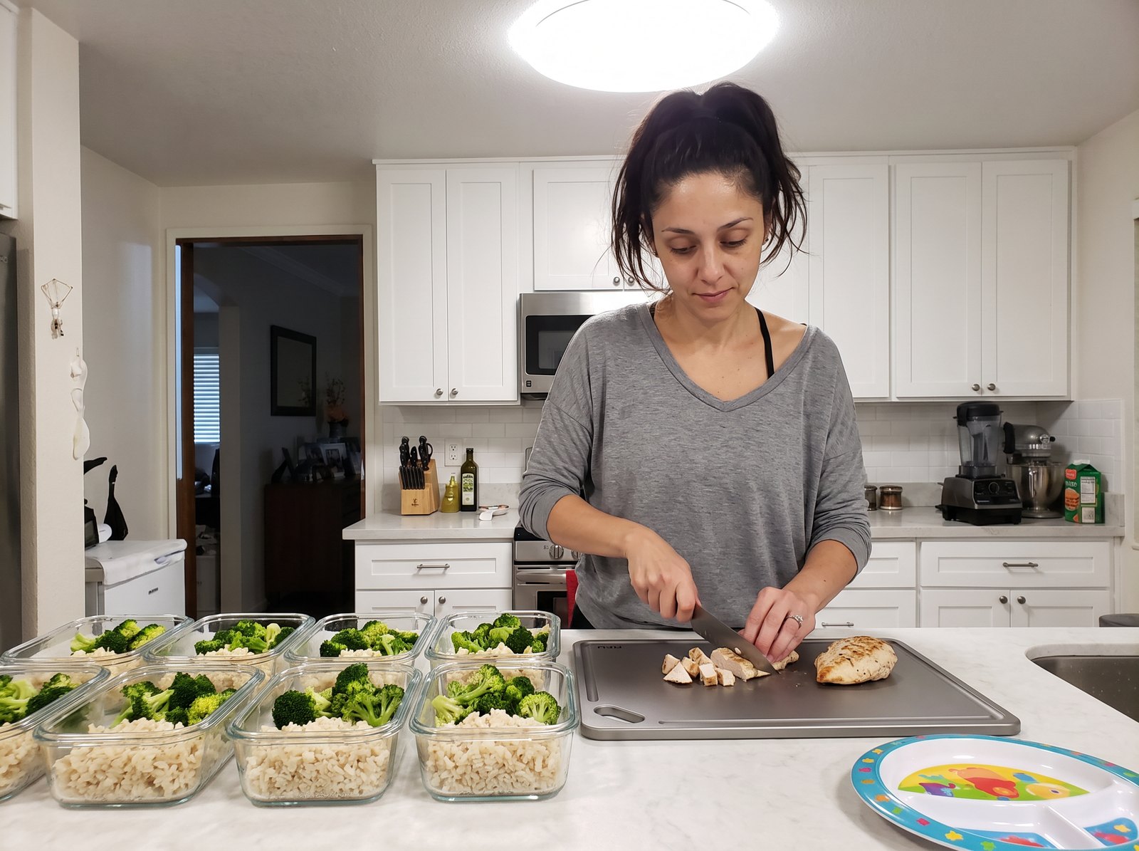 Jess dicing chicken on the Kiru board with a row of filled meal-prep containers