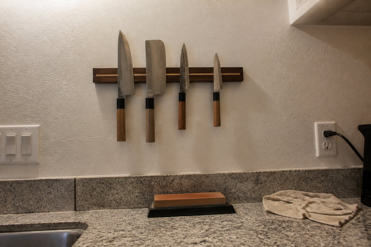 Japanese knives on a magnetic strip above a kitchen counter