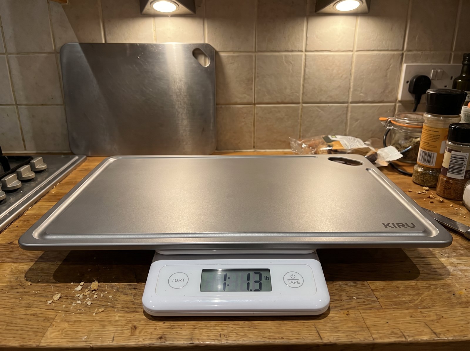 The Kiru titanium board on a kitchen scale reading 1.3 lb