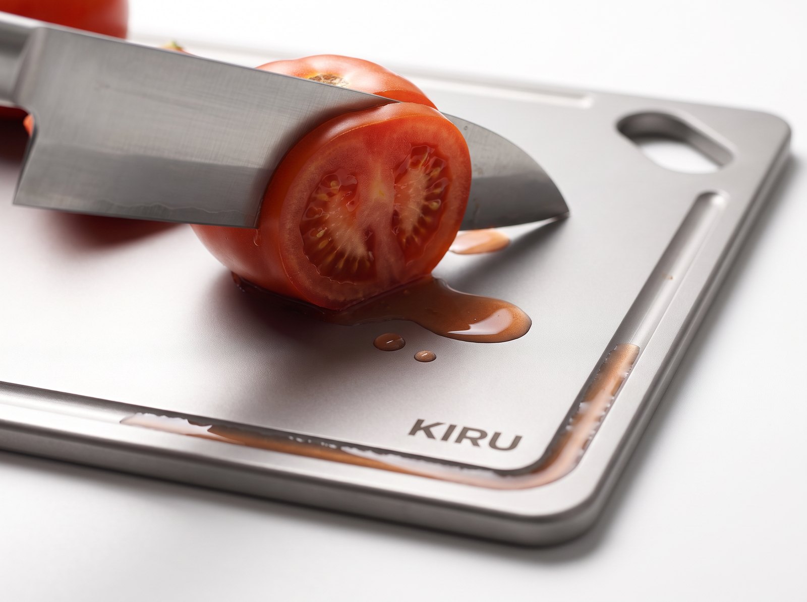 Knife slicing a tomato on the Kiru titanium board